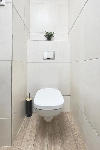 a white bathroom with a toilet and a plant at Trigon Palace in Budapest