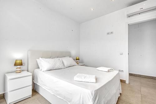 a white bedroom with a bed and a night stand at Senna in Jávea