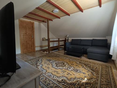 a living room with a blue couch and a rug at Domek pod dębem in Wysoka Lelowska