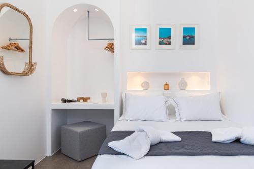 a white bedroom with a bed and a mirror at Aitheras Luxury Suites in Protorgia