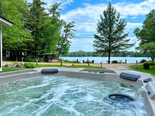 a hot tub in a backyard with a view of the water at 91WR Lake vibes and views at this waterfront home in the the White Mountains! Rest, relax, explore! in Whitefield