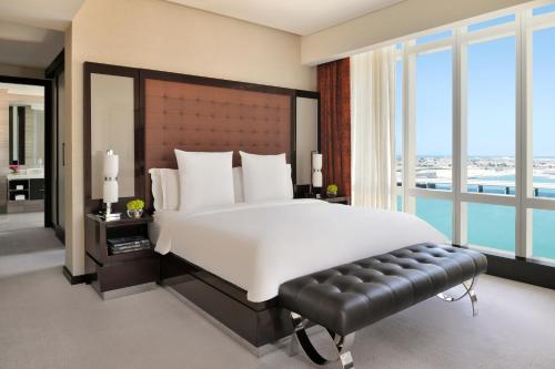 a bedroom with a large bed and a large window at Rosewood Abu Dhabi in Abu Dhabi