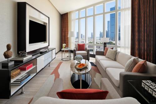 a living room with a couch and a tv at Rosewood Abu Dhabi in Abu Dhabi