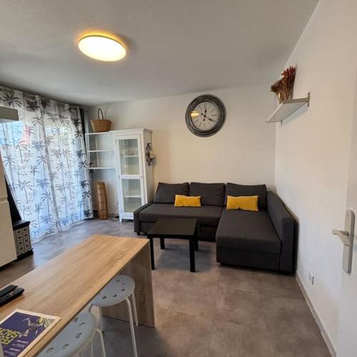 un salon avec un canapé et une horloge au mur dans l'établissement appartement terrasse et piscine, à Montpellier