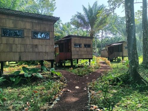 a row of huts in a forest with trees at Hotel Campismo Praia Grande in Monte Carmo