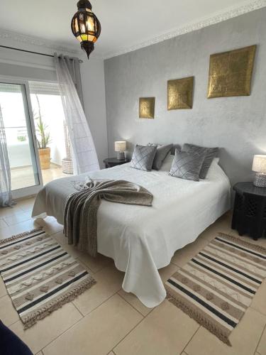 um quarto com uma cama grande e lençóis brancos em Assilah VIP em Asilah