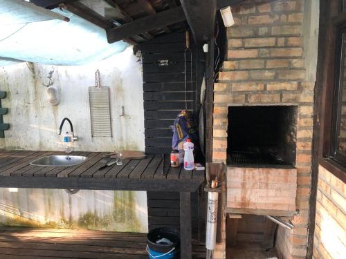 uma cozinha exterior com um lavatório e uma lareira de tijolos em Linda Casa frente mar, pé na areia, Itapema SC, Ar, Wi-fi, Smart Tv em Itapema