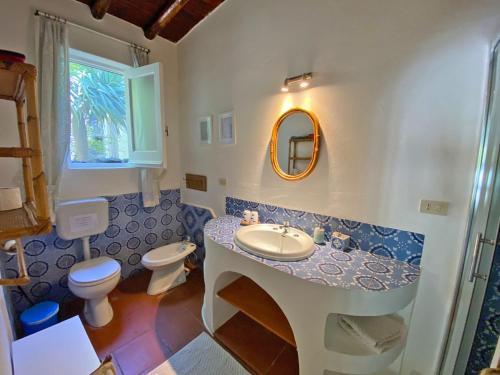 a bathroom with a sink and a toilet and a mirror at Casa Scirocco Lipari in Lipari
