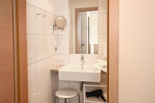 a white bathroom with a sink and a mirror at Hotel Kiekenstein in Stahle