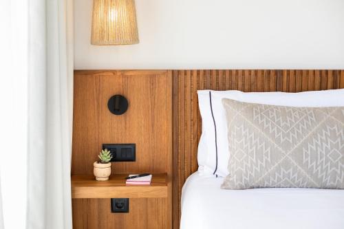 ein Schlafzimmer mit einem Bett und einem Nachttisch mit einer Pflanze in der Unterkunft Hotel Playa Sur Tenerife in El Médano