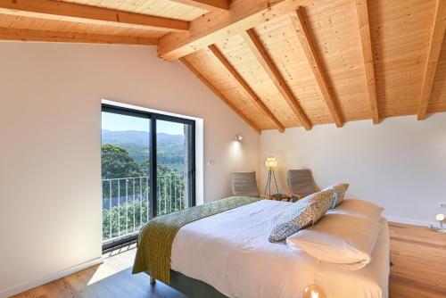 a bedroom with a bed and a large window at Casas das Olas in Arcos de Valdevez