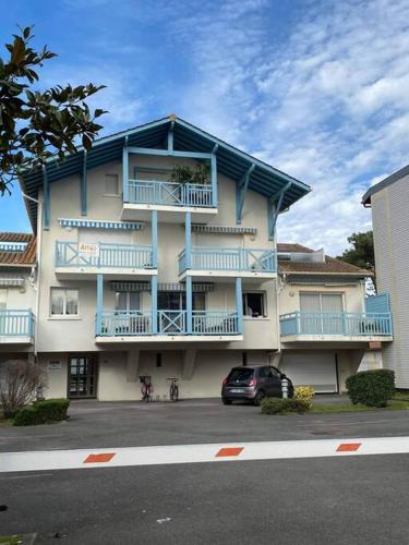 un bâtiment avec des balcons bleus et une voiture garée devant dans l'établissement APPARTEMENT T2 proche de l'océan, à Capbreton
