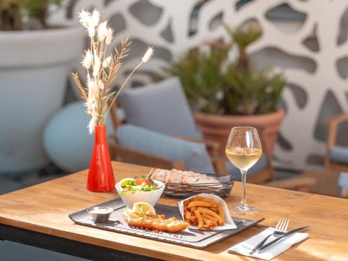 a table with a plate of food and a glass of wine at Holiday Inn Toulouse Airport by IHG in Blagnac
