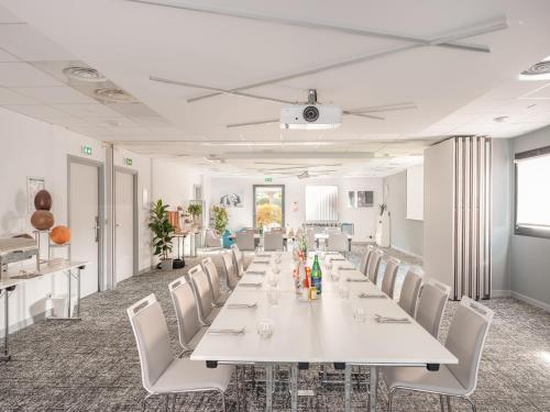 a conference room with a long table and white chairs at Holiday Inn Toulouse Airport by IHG in Blagnac
