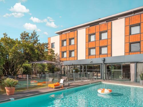 - une vue sur l'extérieur d'un bâtiment avec piscine dans l'établissement Holiday Inn Toulouse Airport, an IHG Hotel, à Blagnac