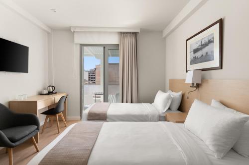 a hotel room with two beds and a desk at Gallery Central Piraeus Port in Piraeus