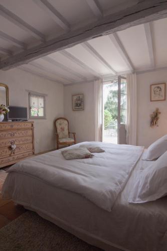 une chambre avec un grand lit blanc et une fenêtre dans l'établissement Au Bel Air, à Clermont-Pouyguilles