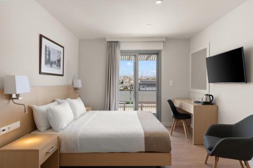 a hotel room with a bed and a desk and a window at Gallery Central Piraeus Port in Piraeus
