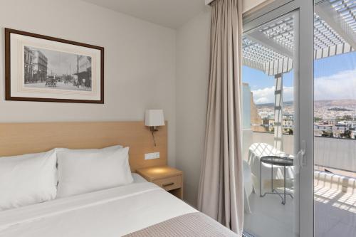 a hotel room with a bed and a balcony at Gallery Central Piraeus Port in Piraeus