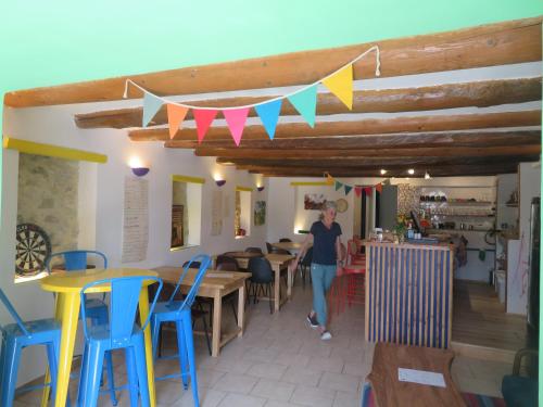 une femme qui marche dans une pièce avec des tables et des chaises dans l'établissement Auberge de la petite casserole, à Revest-des-Brousses