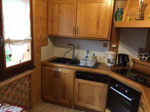 une cuisine avec des armoires en bois et un évier dans l'établissement Appartement charmant pour 4 pers. au Grand Bornand avec balcon ensoleillé, animaux admis - FR-1-467-36, au Grand-Bornand