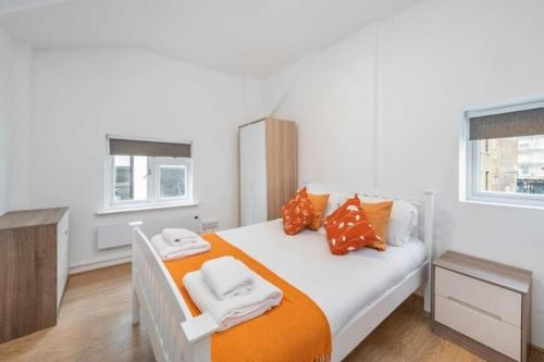 1 dormitorio con 1 cama con almohadas de color naranja y blanco en The Cutesy - Fitzrovia - by Frankie Says, en Londres