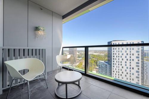 two chairs and a table in a room with a large window at Olympic Park with View Parking near Train in Sydney