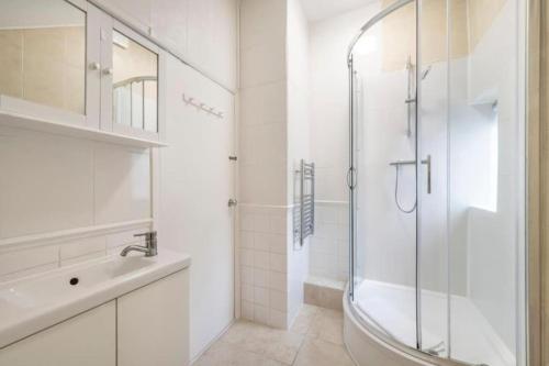 baño blanco con ducha y lavamanos en The Cutesy - Fitzrovia - by Frankie Says, en Londres
