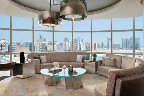 a living room with a couch and a table and large windows at Rosewood Abu Dhabi in Abu Dhabi
