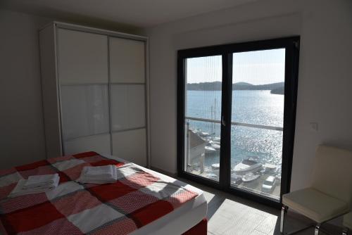 een slaapkamer met een groot raam met uitzicht op het water bij Villa Pina Tisno in Tisno