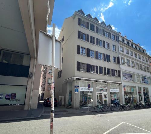 un grand bâtiment blanc dans une rue de la ville avec un panneau dans l'établissement Le Tanneur, Appartement vintage hypercentre, à Strasbourg