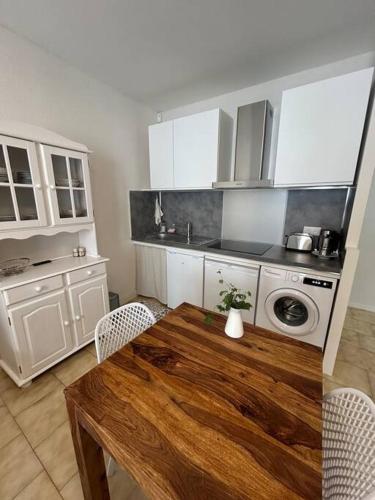 une cuisine avec une table en bois et des armoires blanches dans l'établissement Le flamant rose Arles centre, à Arles