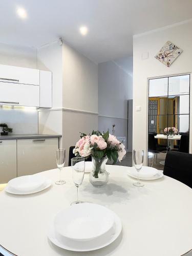 a white table with two plates and a vase of flowers at Trigon Palace in Budapest
