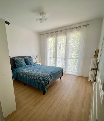 une chambre avec un lit et une grande fenêtre dans l'établissement Fabuleux et charmant appartement idéal en famille, à Drancy