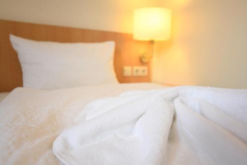 a white bed with a white blanket on it at Hotel Kiekenstein in Stahle