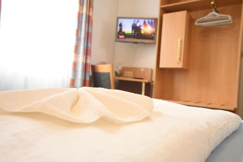 a bed with a white blanket on it with a television at Hotel Kiekenstein in Stahle