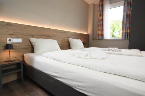 a bedroom with two beds with white sheets and a window at Hotel Kiekenstein in Stahle