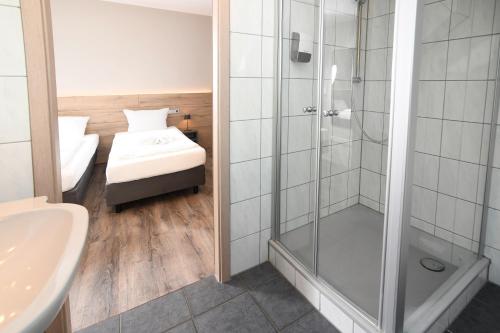 a bathroom with a shower and a bed and a sink at Hotel Kiekenstein in Stahle