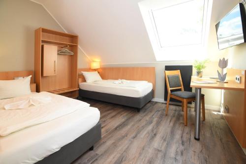 a room with two beds and a desk and a chair at Hotel Kiekenstein in Stahle