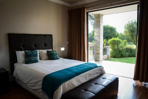 a bedroom with a large bed and a large window at Kingfisher on Vaal, Parys in Parys