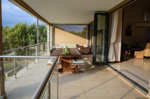an open balcony with a wooden table and glass doors at Kingfisher on Vaal, Parys in Parys