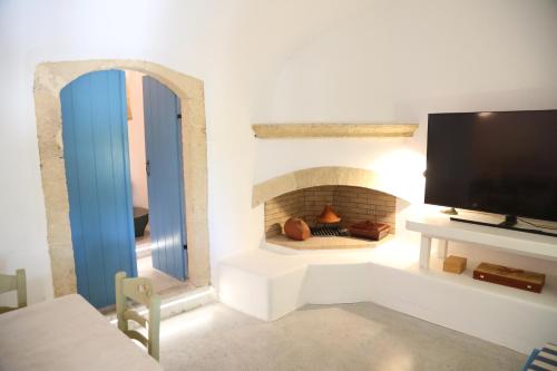 a living room with a tv and a fireplace at Traditional house in Mitata next to the canyon! in Kýthira