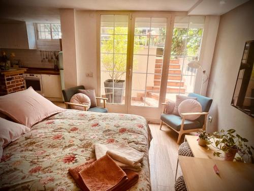 a bedroom with a bed and a kitchen with a window at Loft de estilo industrial con jardín y garaje privados in Valladolid