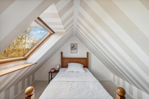 a attic bedroom with a bed and a window at Landhaus Köhn in Giekau