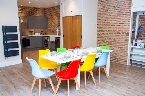 a dining room with a white table and colorful chairs at The Kennels in Hexham
