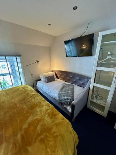 a bedroom with two beds and a tv on the wall at Lochindaal Hotel in Port Charlotte