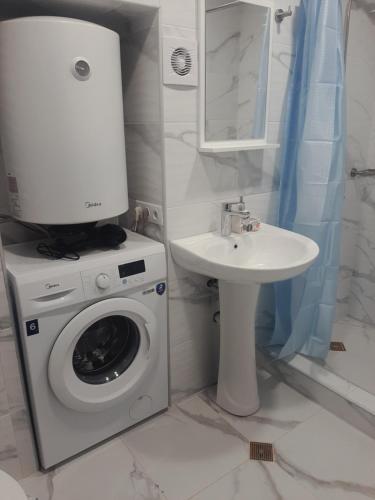 ein Badezimmer mit einer Waschmaschine und einem Waschbecken in der Unterkunft "Vera old City" in Tbilisi City