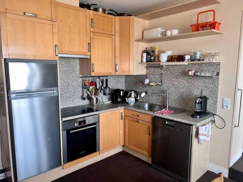 une cuisine avec des armoires en bois et un réfrigérateur en acier inoxydable dans l'établissement Appartement Vue Mer, à Trouville-sur-Mer