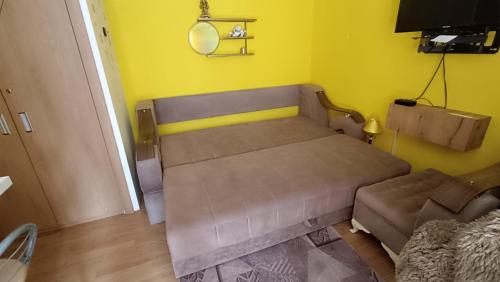 een kleine slaapkamer met een bed en een bank bij Vaja apartman in Vrnjačka Banja