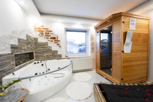 baño con bañera grande y pared de piedra. en Luxe Apartments en Ljutomer